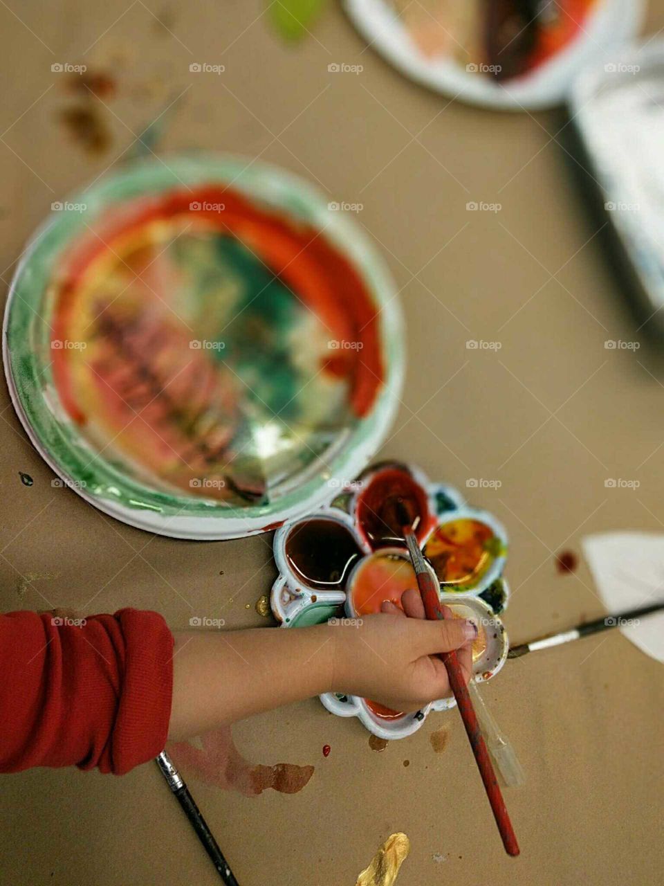 A young child paints autumn leaves.