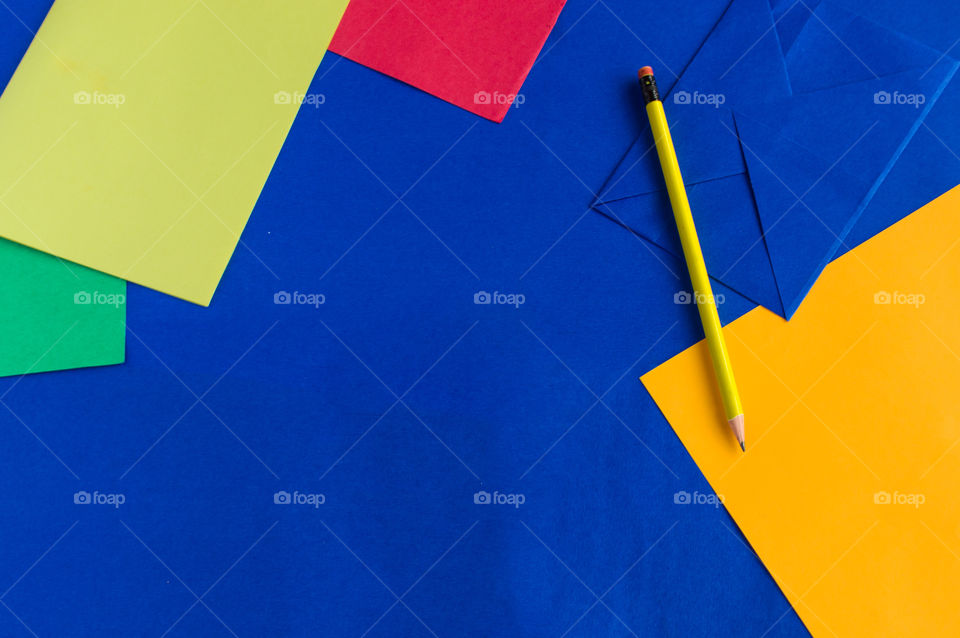 Colorful envelopes,papers and yellow colored pencil arranged on a blue colored paper.