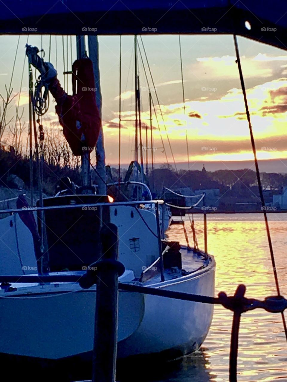 Our sailboat, the „Salvation“ tied to the shore at Newtown Creek in Long Island City, Queens, NY makes a dark contrast against the shimmering waves of the East River in the golden hour of sunset on a late afternoon in 2018. Hypnotic Productions