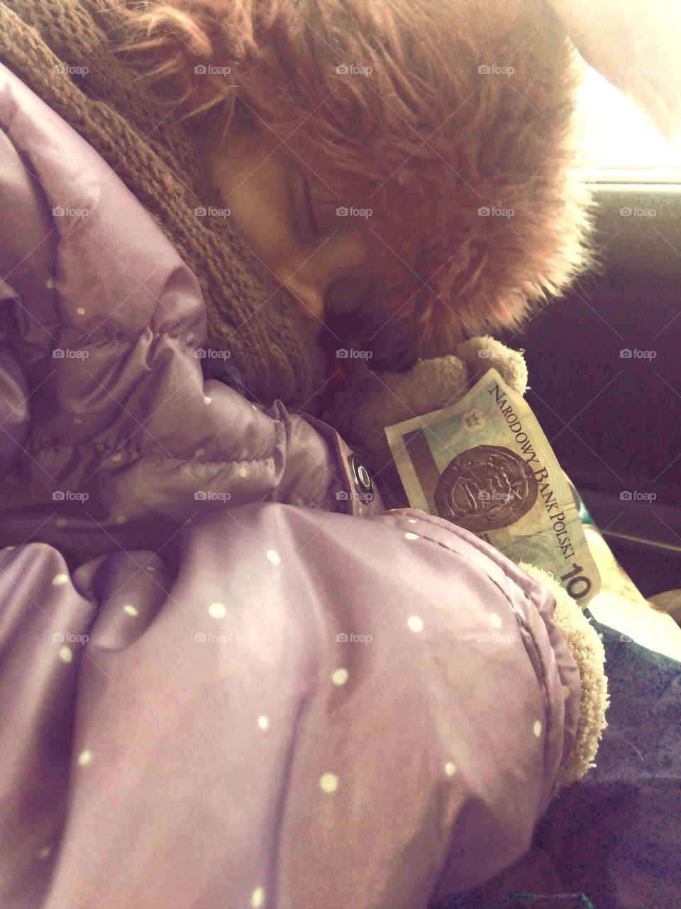 Child holding currency in hand while sleeping