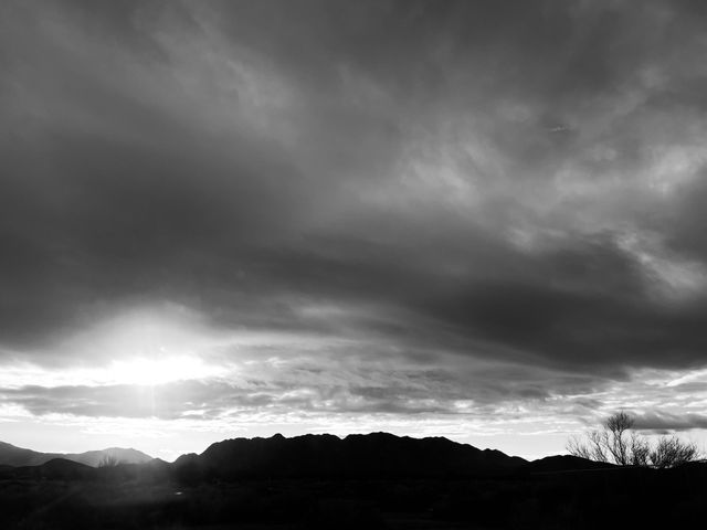 A black and white photo of mountains with clouds above. 
