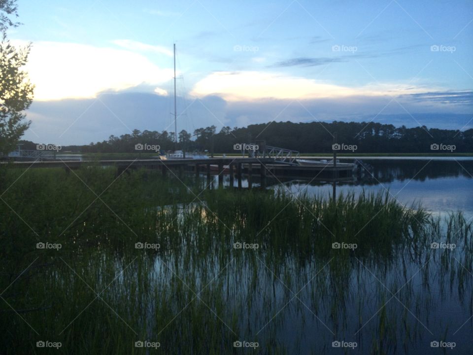 Pier, boats, and reeds in a lake at dusk. 
