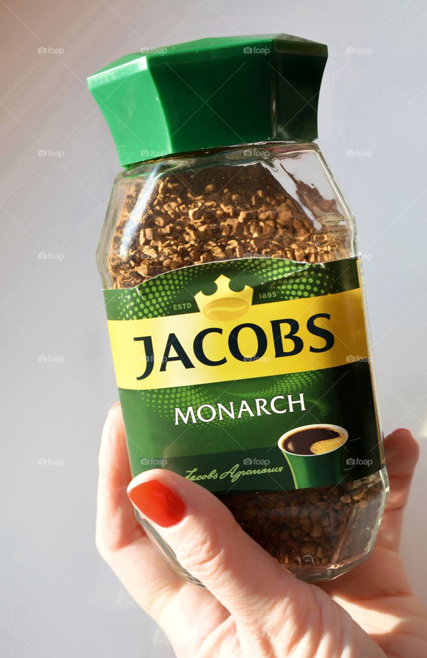 coffee Jacobs in glass bank in the female hand on a white background