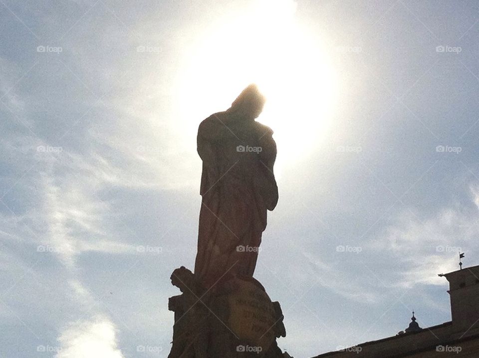 Sun shine behind saint sculpture 