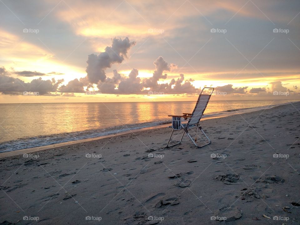 Chair on a beach with a sunset.