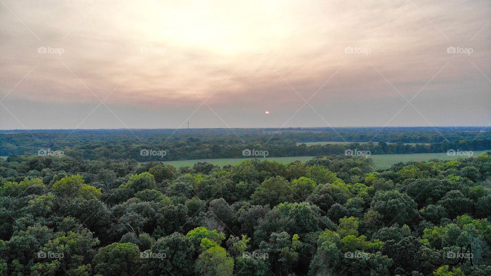 The setting sun on the horizon showing through the clouds.