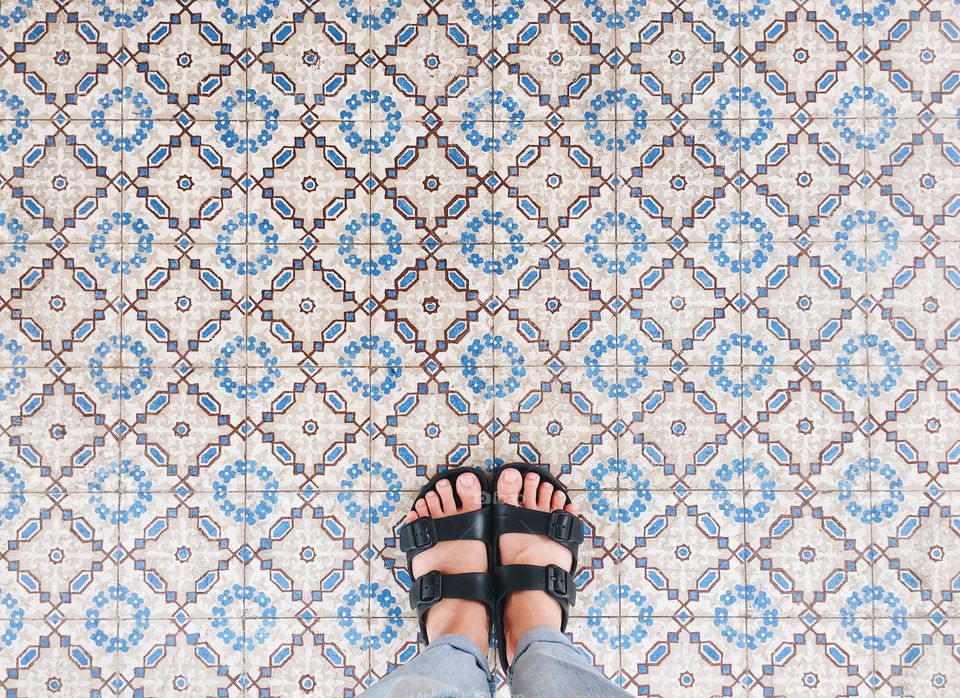 Selfie of feet in sandals shoes on pattern floor background