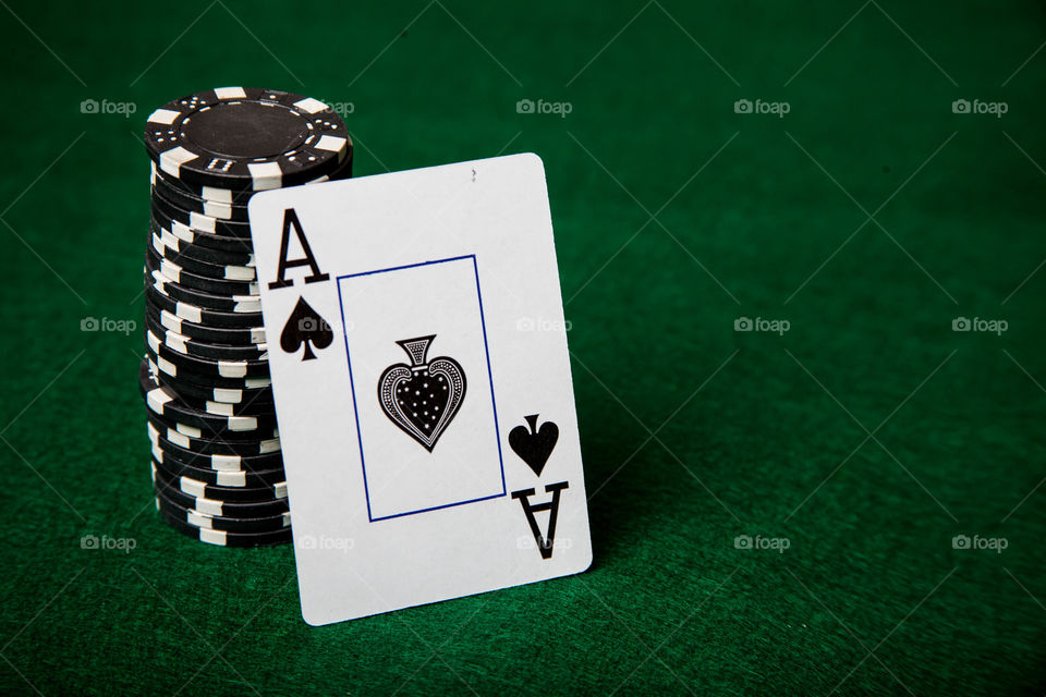 Ace of spades sitting on poker. This is a photograph of an Ace of Spades sitting against a stack of black poker chips.