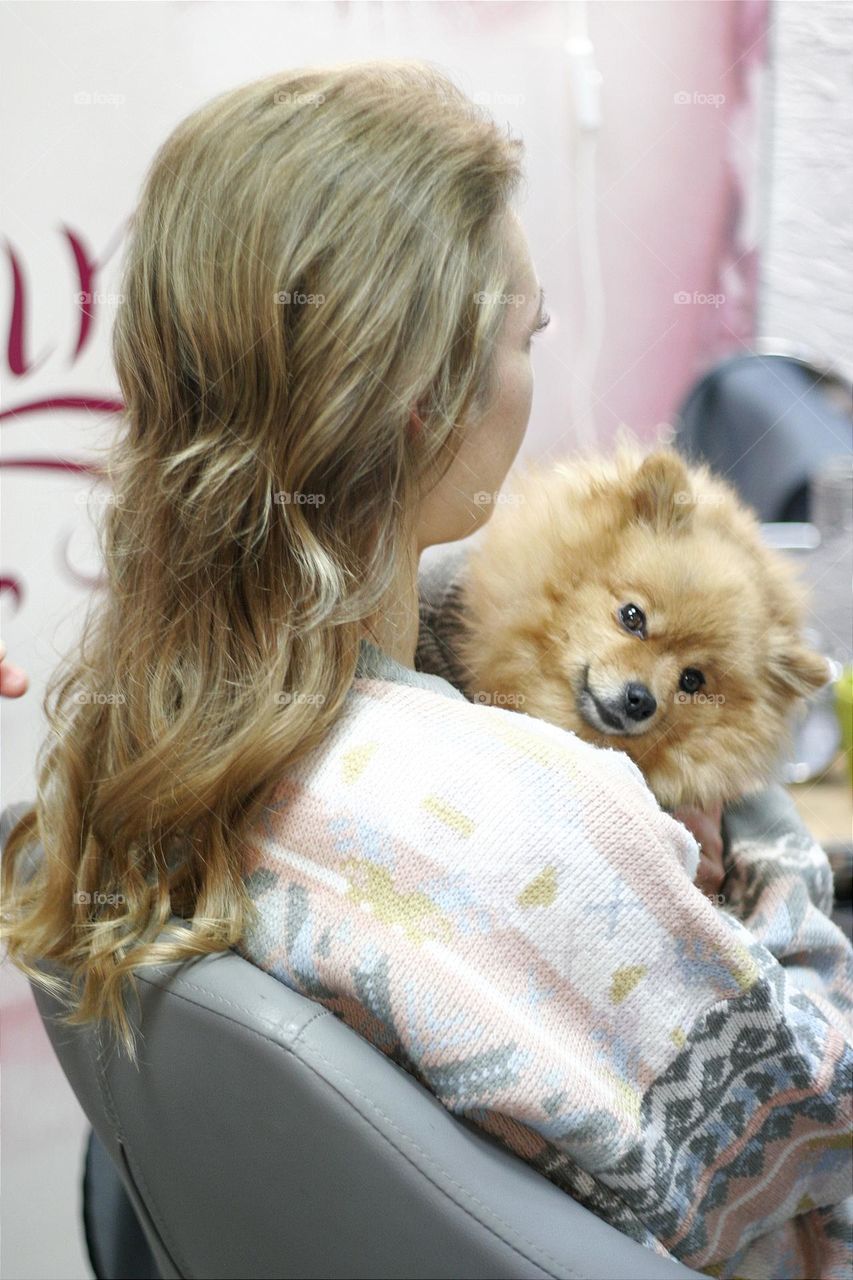 a girl with a dog brings beauty in a beauty salon