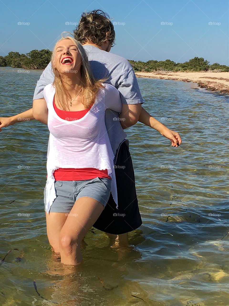 Couple carrying back to back in sea and laughing