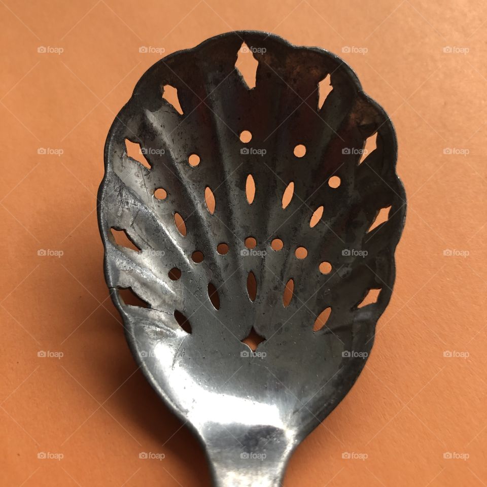 Old metal spoon on orange background 