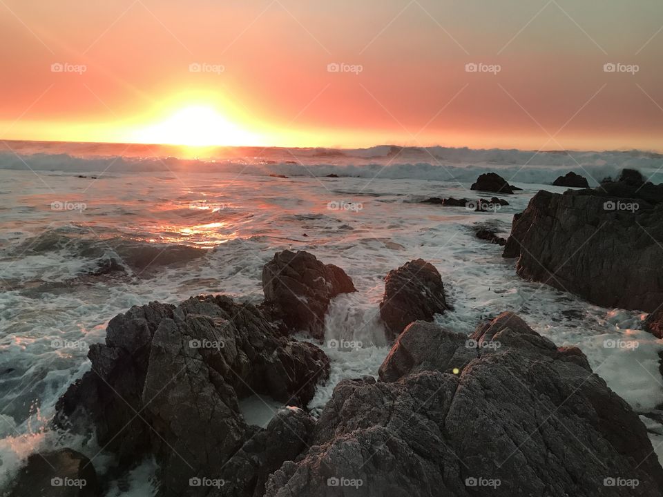 A Pacific sunset captured from the rocky shores of Pebble Beach, CA. The crashing waves created a white blanket for the sunset to bring color to. A very unique sunset