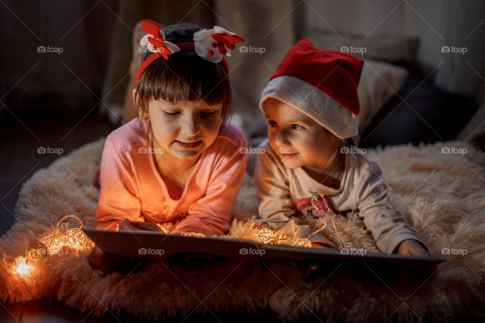 Little sisters reading a book at Christmas time 