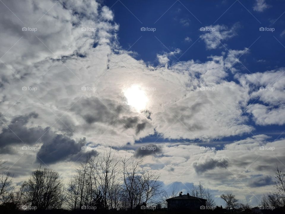 sun peeking through clouds  and bright blue sky