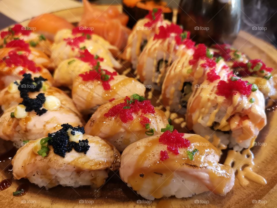 Close-up of burned salmon sushi and roll on wooden plate. Japanese food.