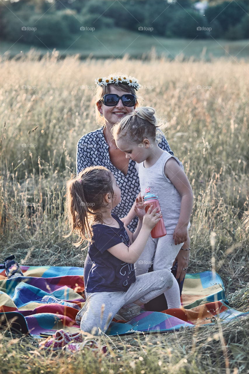 Family spending time together on a meadow, close to nature. Parents and children playing together, making coronet of wild flowers. Candid people, real moments, authentic situations