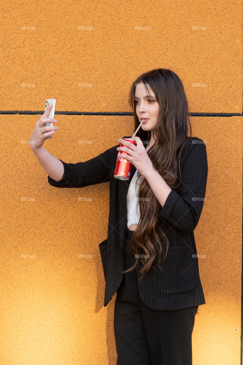 A teenager girl makes selfie with red Coca-Cola can. Modern culture