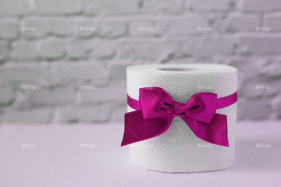 Toilet paper with the pink bow on the white background