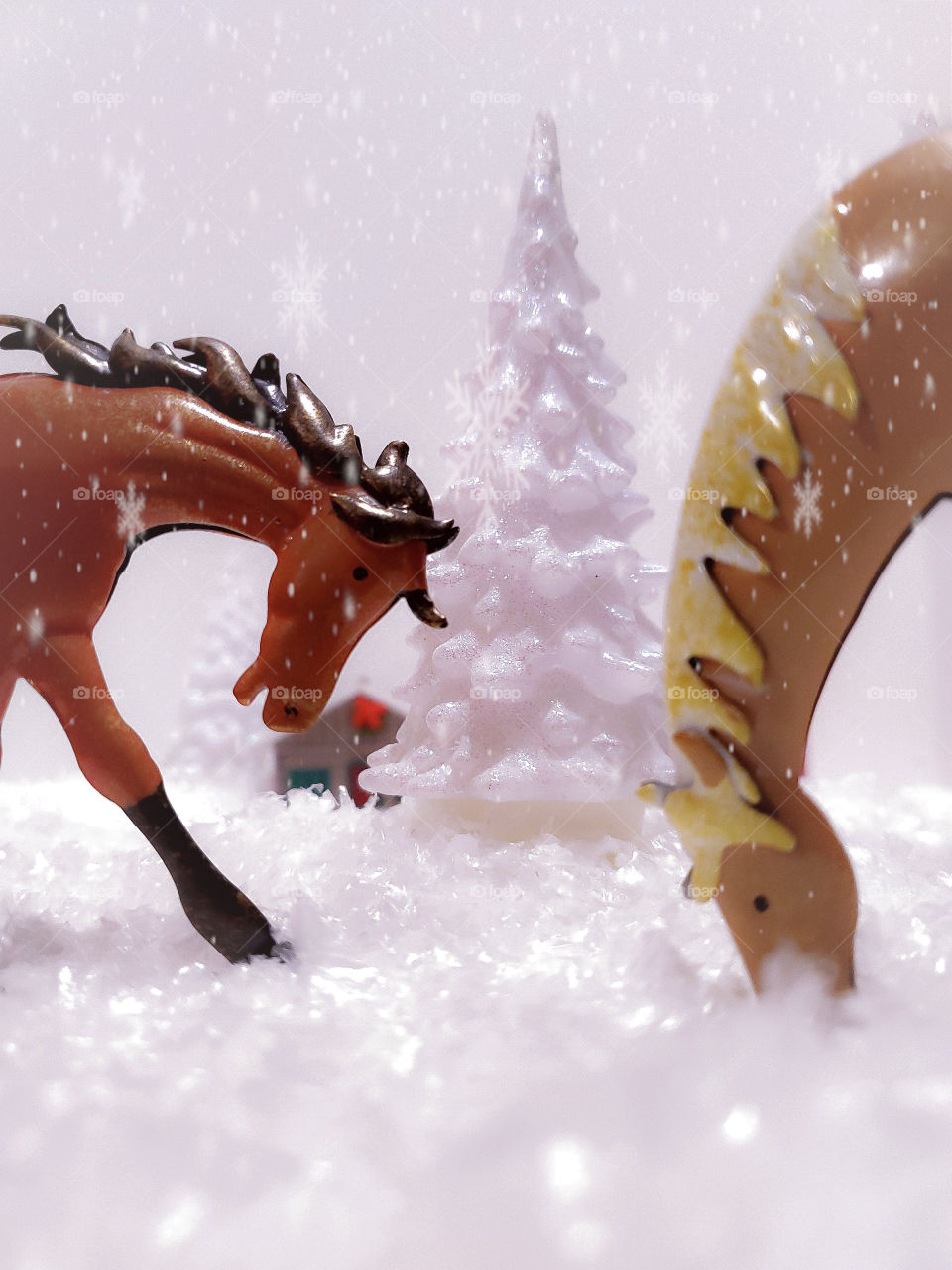 White Christmas miniature scene with a snow covered pine tree, two horses, a log cabin and snow.