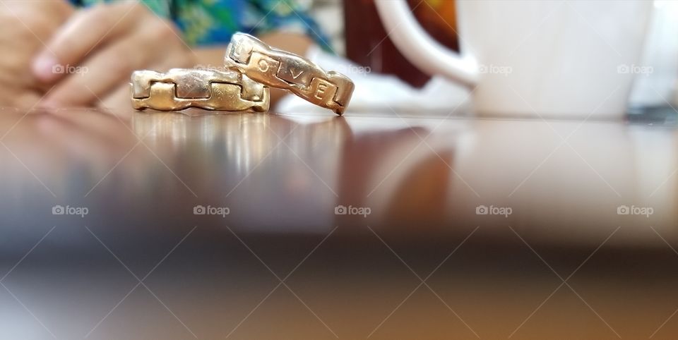Two gold wedding rings on a coffee table, symbolizing love through the simple things.