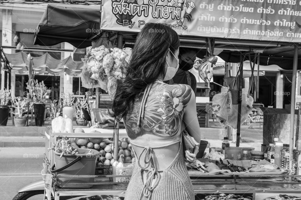 An attractive Thai woman with an unusual tattoo on her back at a street food stall in Thailand Southeast Asia