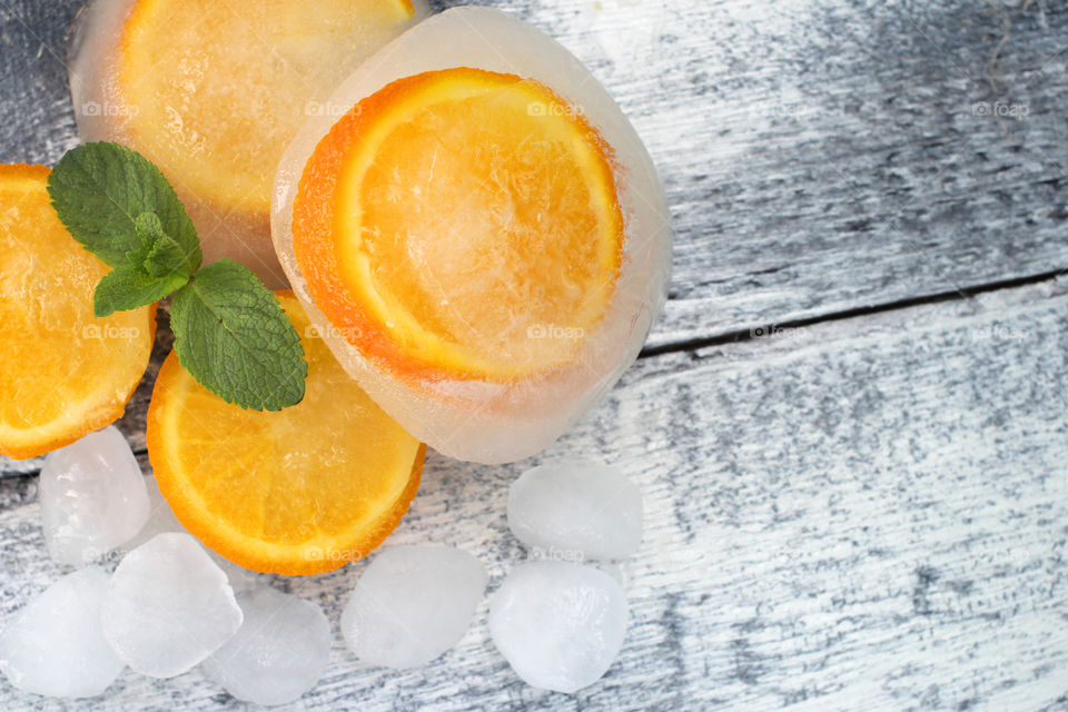 Oranges,mint leaves and ice cubes on wood