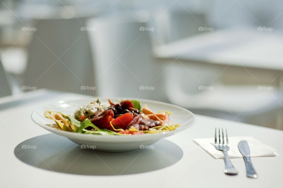 close-up of a young man eating a salad in a light kitchen