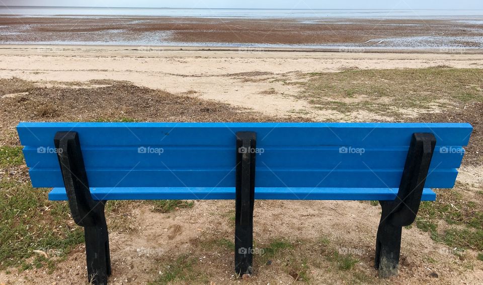 Blue bench on remote ocean beach seascape