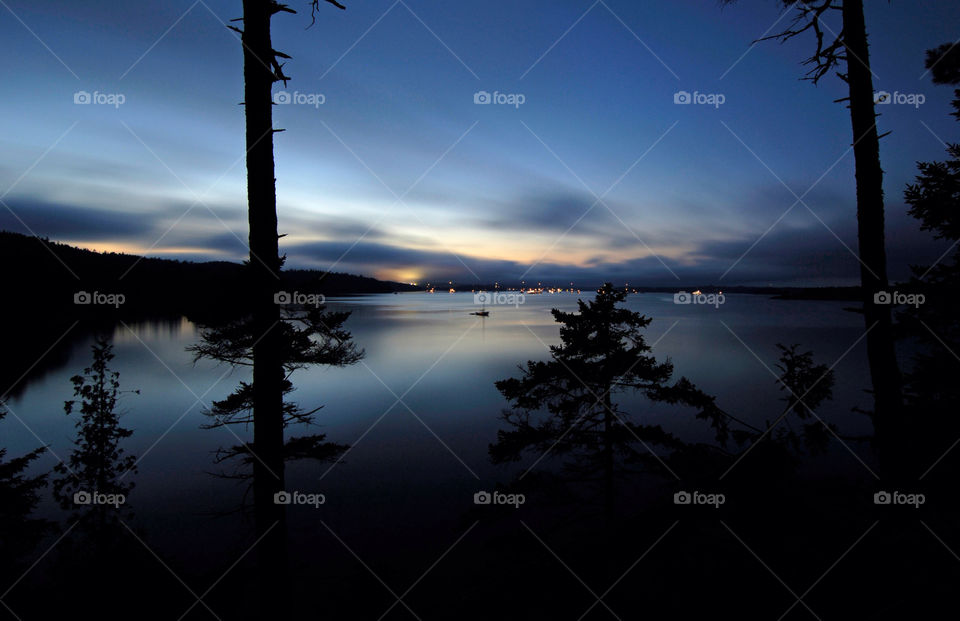 Sailboat sits on a serene day at sunset across the harbor from Castine