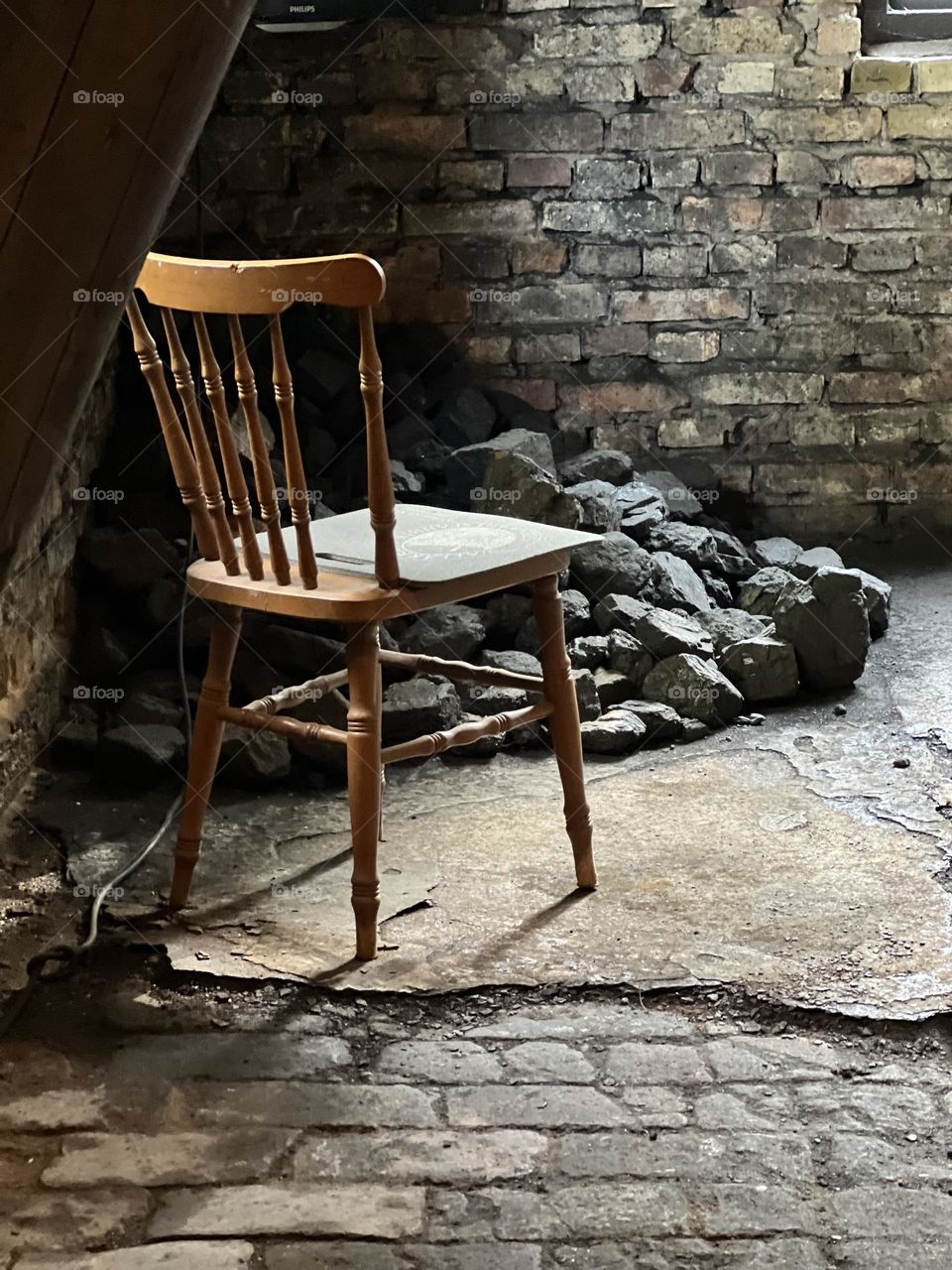Old wooden chair standing in the sun by old bricks in building