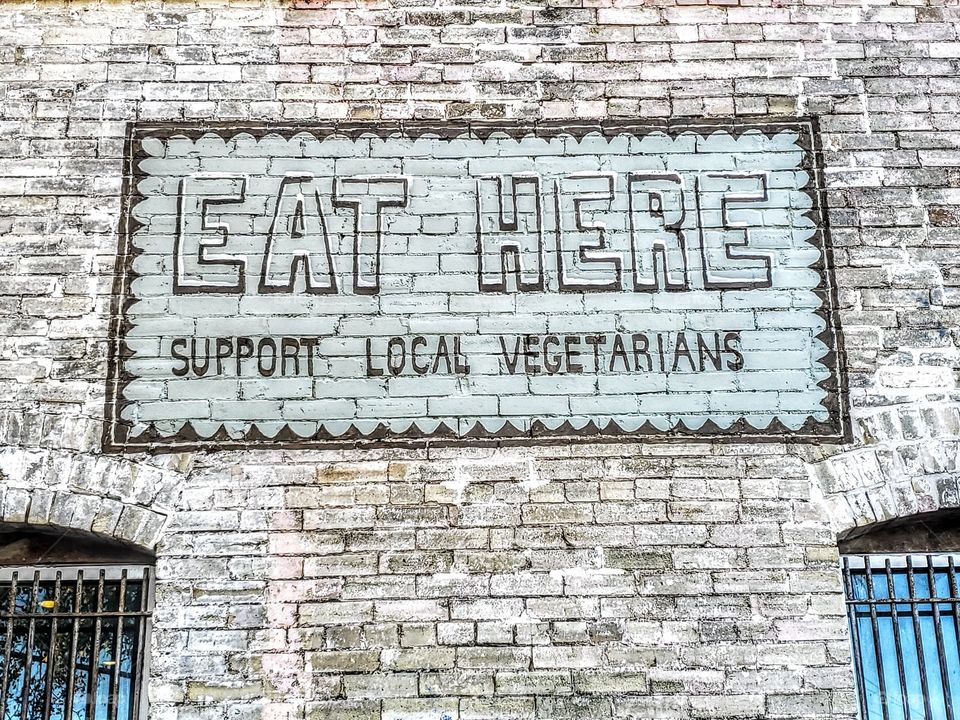 Painted sign on brick wall: Support local vegetarians