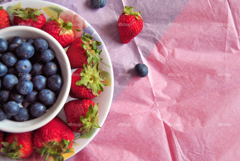 Blueberries in ramekin and strawberries in plate flat lay