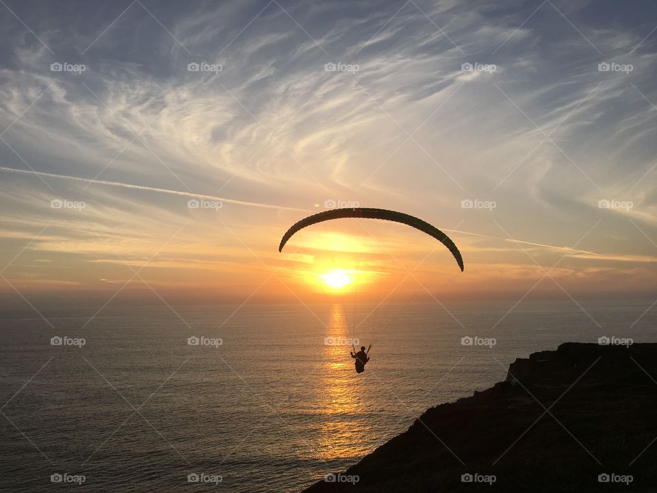 Person paragliding during sunset