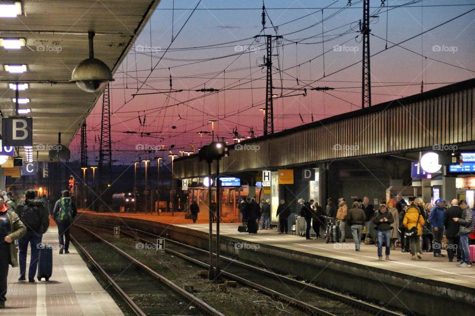 People are waiting for their train at the train station at sunset