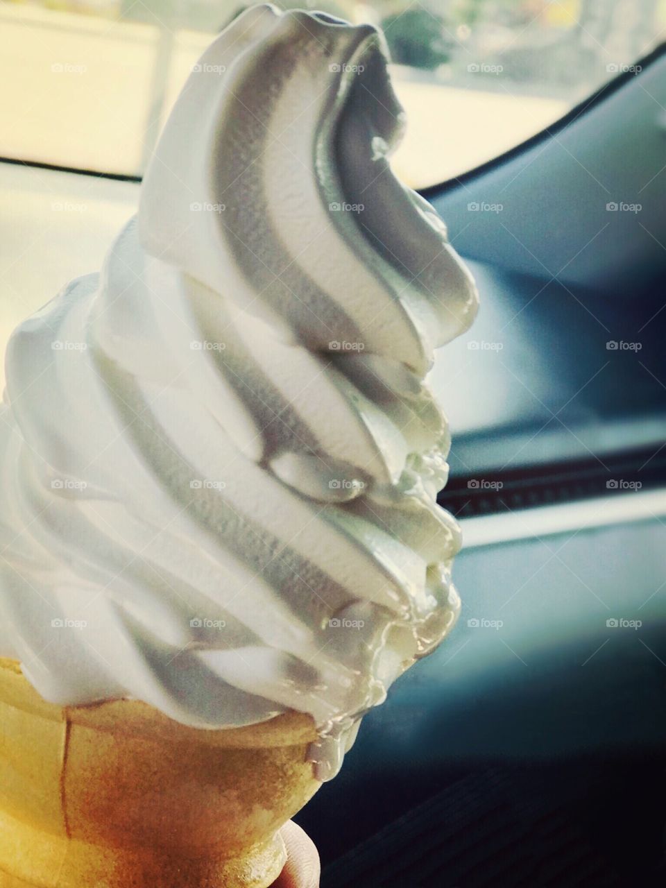 Delicious creamy vanilla ice cream cone melting in the sunlight on a hot summers day 