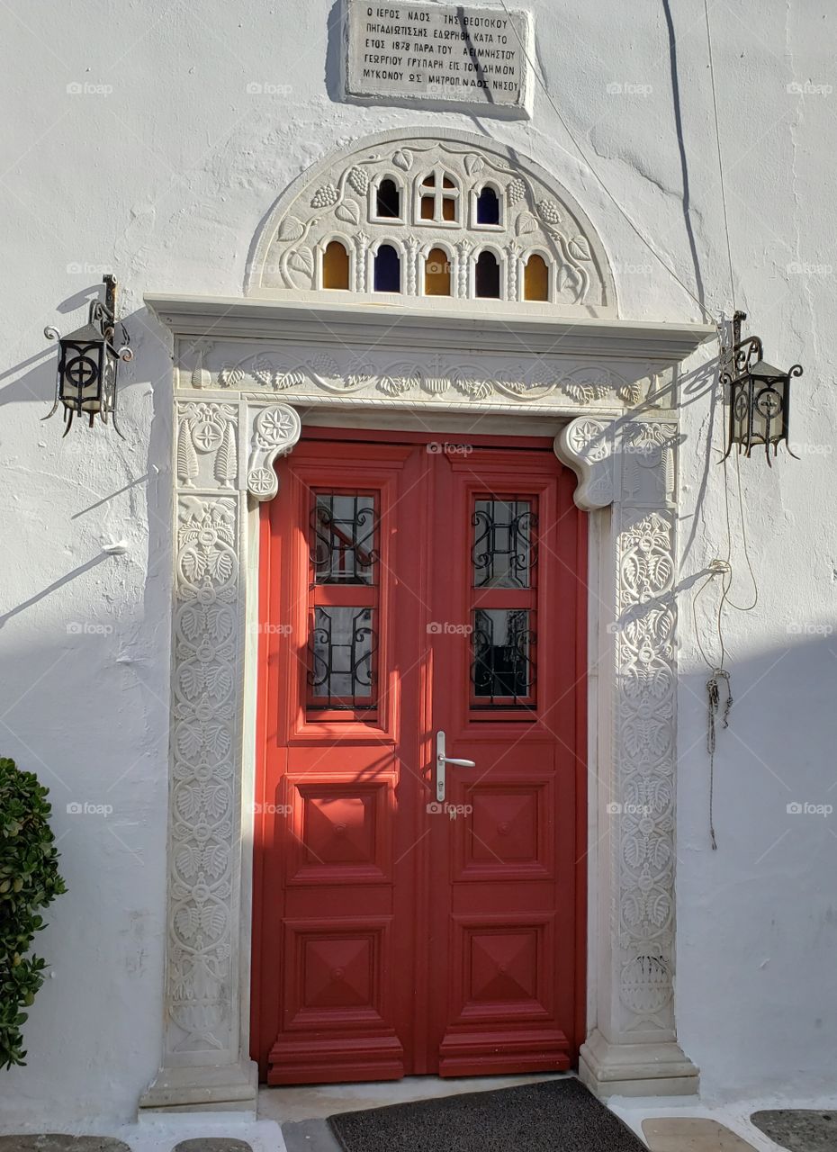 Red door with beautiful architectural design on white doorframe and building in Morocco, Africa