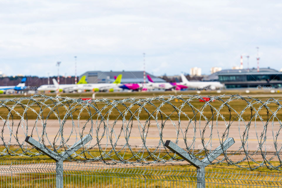 coronavirus pandemic quarantine, flights canceled, behind a barbed wire fence visible aircraft parked for a long time, selective focus