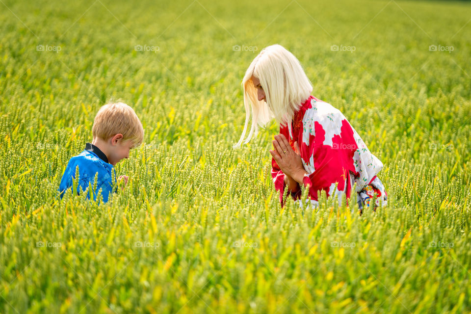 A blond woman with a son, dressed in kimono, in a cereal field.