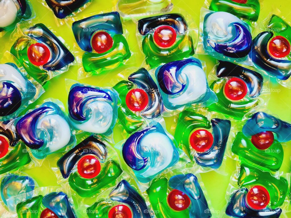 Tabs of laundry detergent scattered on a green background