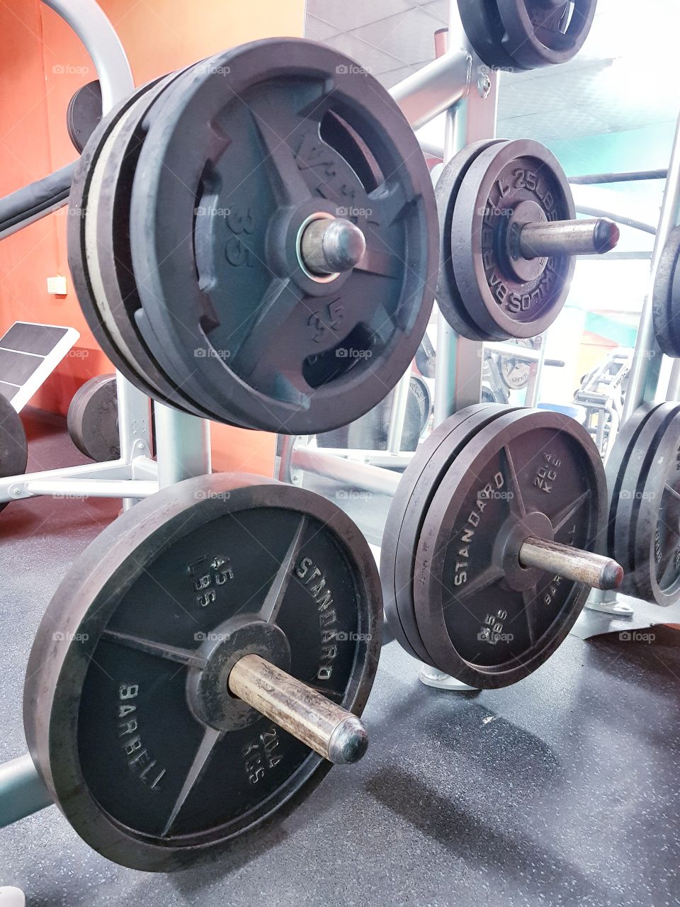 Gym weight plates stacked on squat rack displaying strength, endurance, an escape and happiness