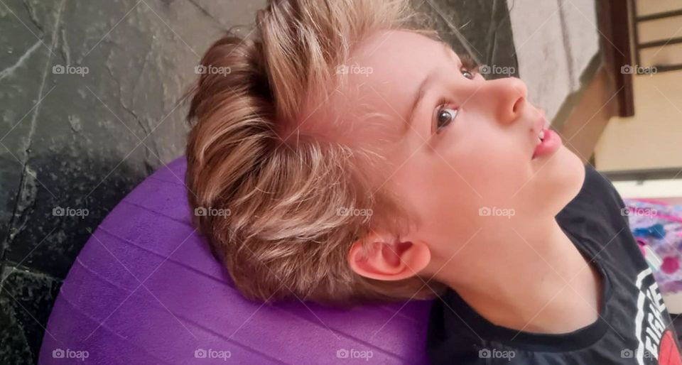 Boy lying on Purple Pilates Ball.
Garoto deitado em Bola de Pilates de coração Roxo.