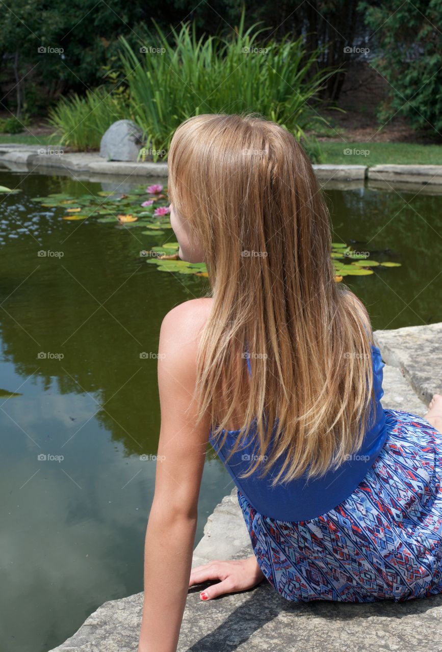 Rear view of girl sitting at lake side
