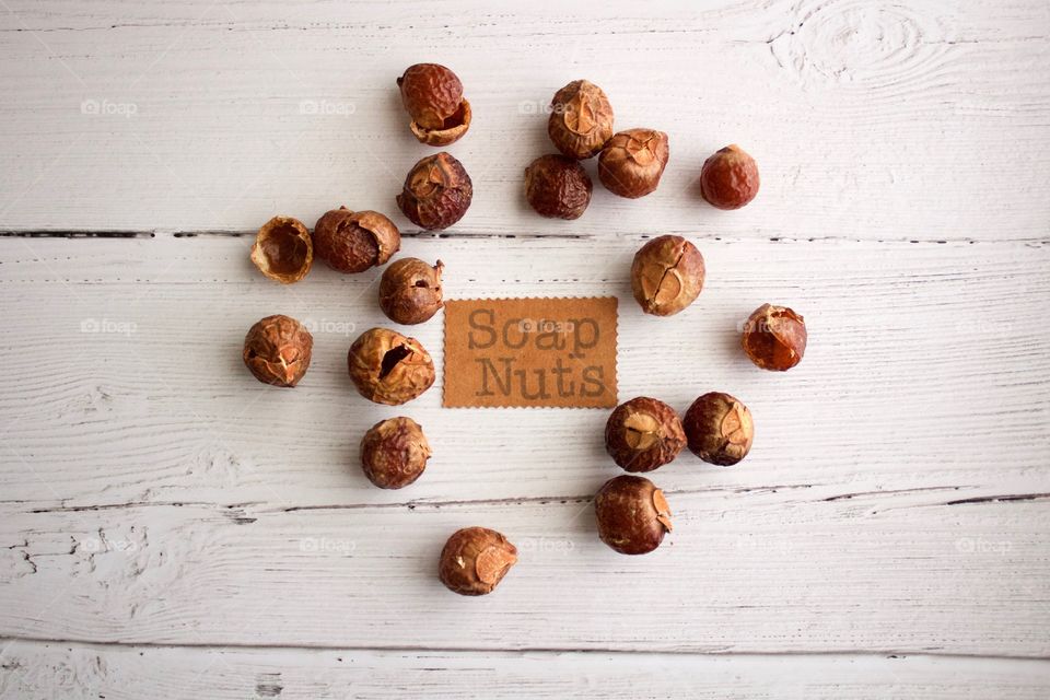 Soap nuts or soap berries on weathered white wooden background with identification placard in natural light