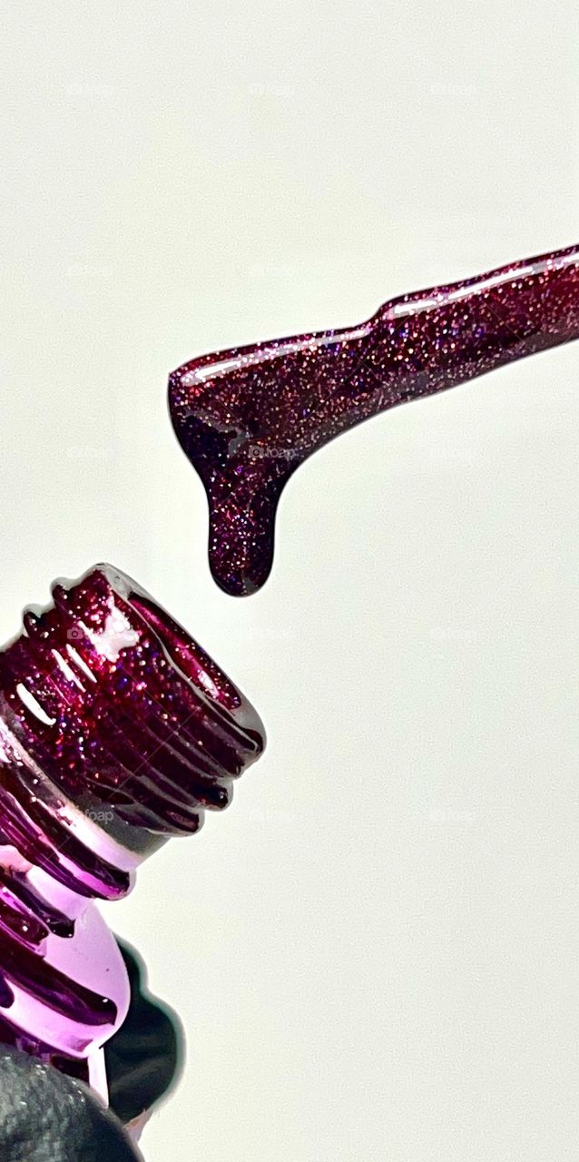 A deep cherry-purple shade of nail polish generously strewn with micro-glitters of ruby ​​and purple.