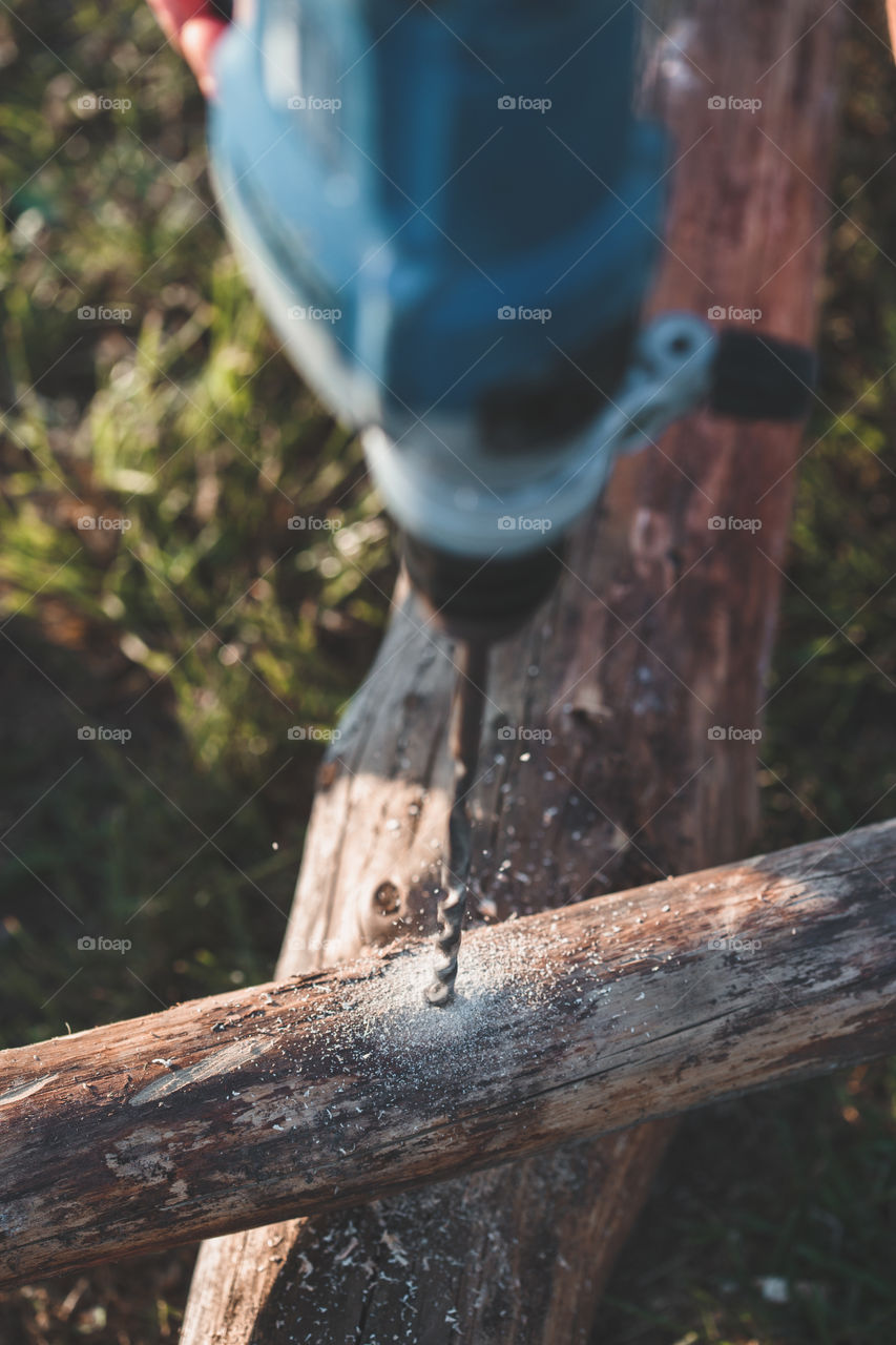 Man drilling hole in timber while working in garden. Real people, authentic situations