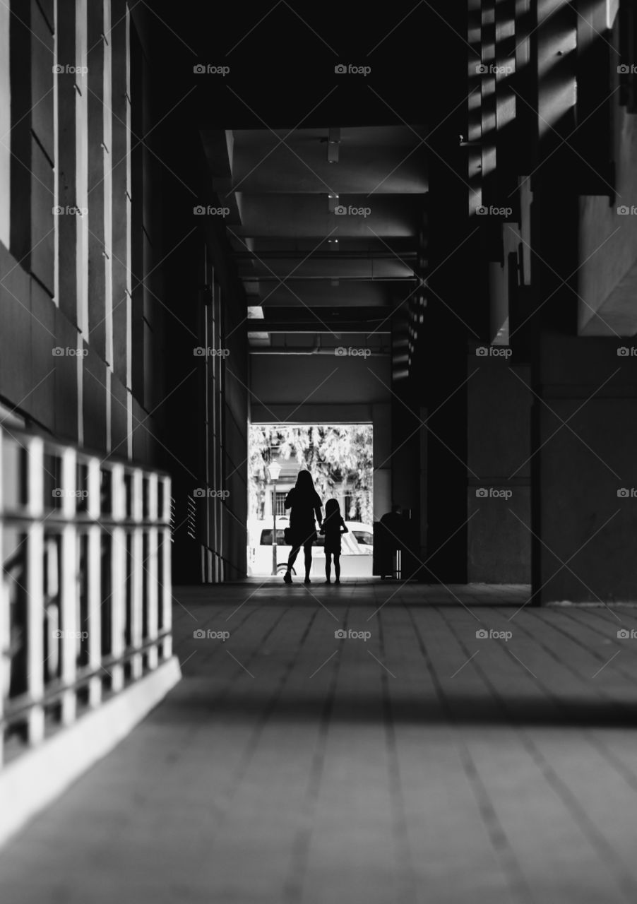 A mother and daughter on their way to cross the street. I waited for them to reach the end of the hall and took a picture.