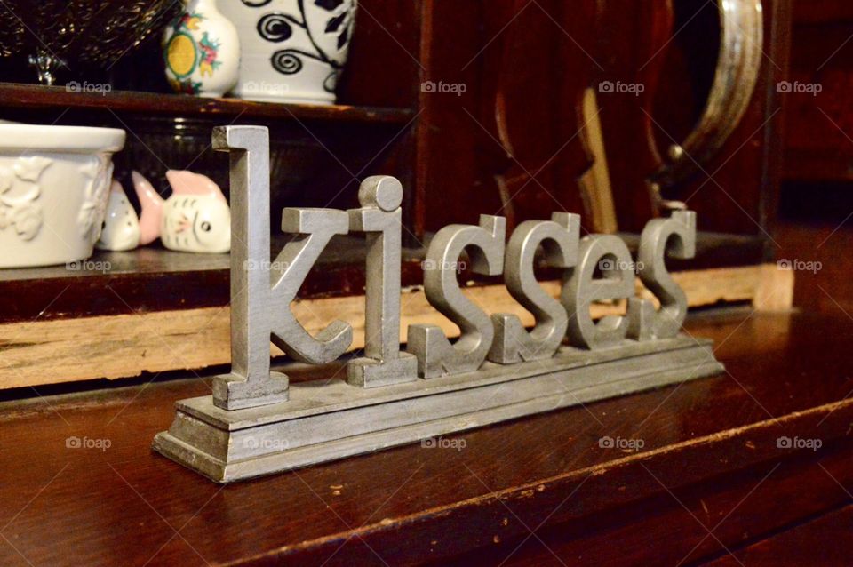 Gray metal Kisses word on a piece of wooden furniture 