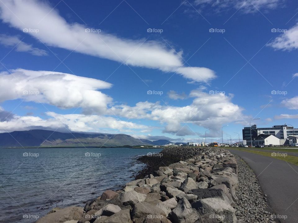 Downtown in Iceland, a cityscape in the background of the large bay surrounded by smooth rocks. 