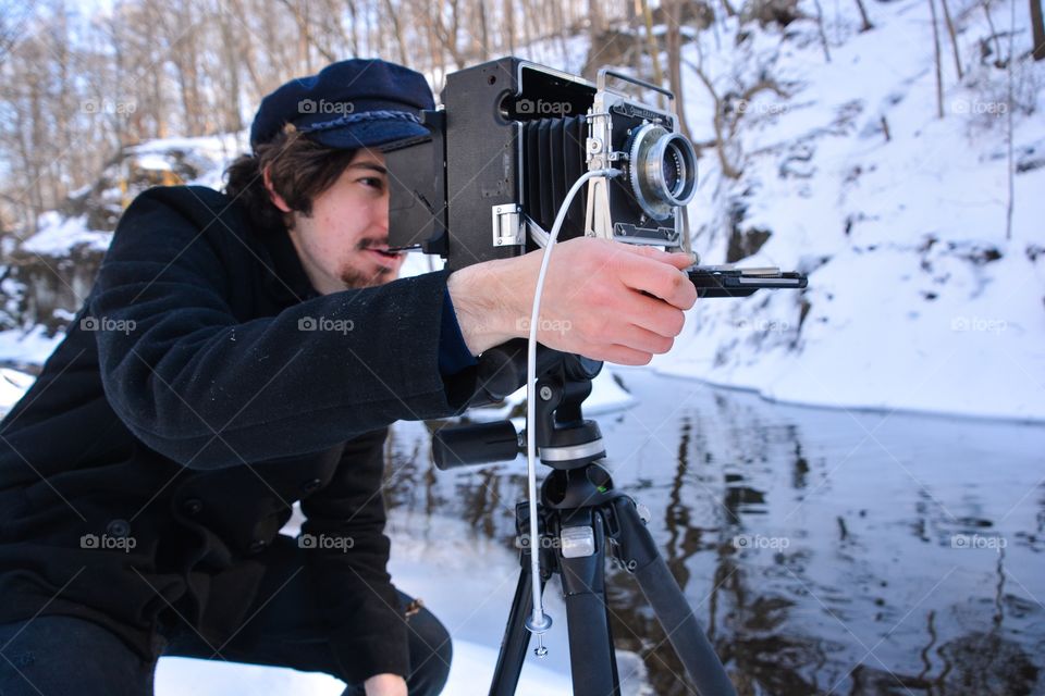 A man uses the old fashion photography equipment of a film camera to capture his image 