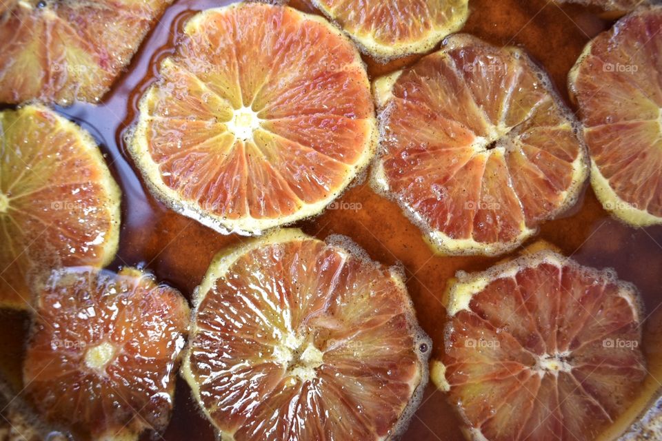Top view of thinly sliced blood oranges soaking in cinnamon syrup 